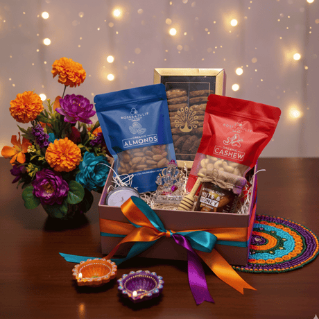 Gift box with almonds, cashews, and flowers on a wooden table with a decorative background.