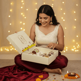 Woman opening a box of Diwali gift hamper with pure and healthy Ghee, honey, Coconut oil, Cashew & Almonds