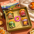 Illustrated Diwali gift box partly open to reveal four dry fruit jars and a lotus diya
