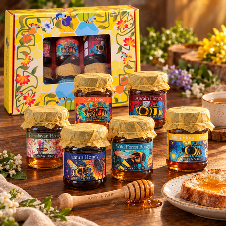Six Roses & Tulip honey jars displayed with their illustrated gift box, a wooden dipper, toast and tea.